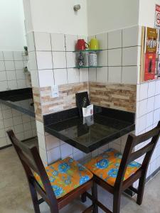 uma cozinha com duas cadeiras e um balcão com uma bancada em Suite 03 - Independente, privativa e aconchegante em Cuiabá