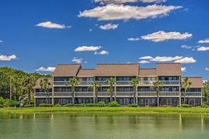 a building with palm trees in front of a lake at Beachy Lakefront Escape - Walk to the Shore! in Destin