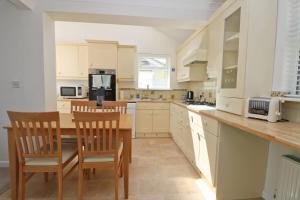 a kitchen with white cabinets and a wooden table and chairs at Holiday home with Estuary Views, parking & balcony in Padstow