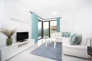 a white living room with a white couch and a tv at Villa Apartments Lela in Rabac