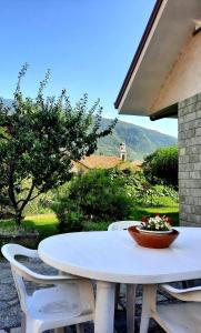 a white table and chairs with a bowl of flowers on it at Casa Vacanze Santa Perpetua in Tirano