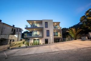 a large white building with balconies on a street at Villa Apartments Lela in Rabac