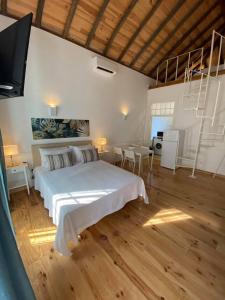 a bedroom with a white bed and a dining area at Faro Downtown Ria Formosa Studios in Faro