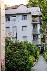 un bâtiment blanc avec un balcon et quelques buissons dans l'établissement Center 4U, à Vrnjačka Banja