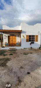 a small white house with wooden doors and windows at Azteca Villas in Treasure Beach