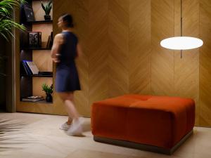 a woman walking in a room next to a orange ottoman at Musik Boutique Hotel - Solo Adultos in Barcelona