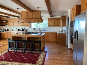 a kitchen with wooden cabinets and a island with bar stools at Villa Alta Vista at Yosemite- Stunning Views and Game Room in Mariposa