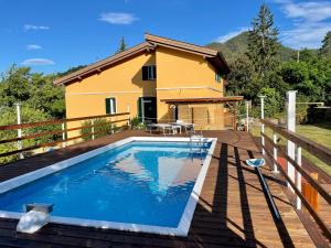 a pool on a deck with a house in the background at Impronte Nel Bosco in Calice al Cornoviglio