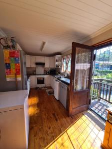 cocina con electrodomésticos blancos y suelo de madera en Natures Cabin, en Hibberdene