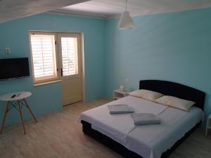 木洛希尼的住宿－Apartments Losinj，一间卧室配有一张带蓝色墙壁的大床