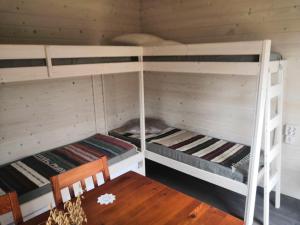 a room with two bunk beds with a wooden table at Mäentaustan aitat in Janakkala