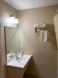 a bathroom with a sink and a mirror and towels at Wayne Motel in Fort Wayne