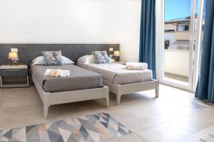 a bedroom with two beds and a balcony at Salaqua Bed and Breakfast in Torre Mozza
