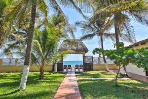 a pathway leading to a resort with palm trees and the ocean at Guatemala Beachfront Villa with Direct Beach Access! in Monterrico