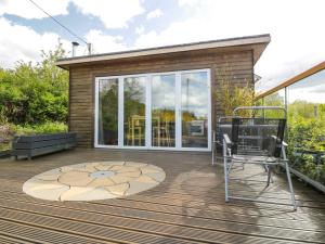 een houten terras met stoelen en een huis bij Blackbrae Cabin in Coatbridge