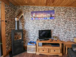 a living room with a stone wall with a fireplace at Blackbrae Cabin in Coatbridge