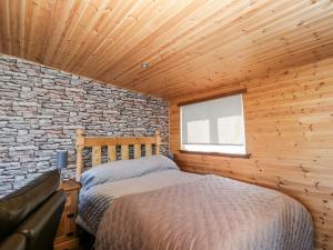 a bedroom with a bed and a brick wall at Blackbrae Cabin in Coatbridge