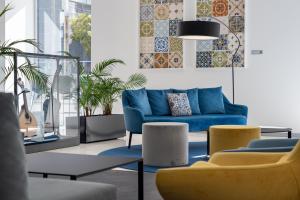 a living room with a blue couch and chairs at Jupiter Lisboa Hotel in Lisbon