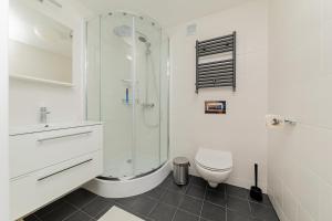 a white bathroom with a shower and a toilet at Hostel Szczelinka in Pasterka