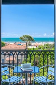 Hotel Villa Ombrosa في مارينا دي بيتراسانتا: طاولة وكراسي على شرفة مطلة على المحيط