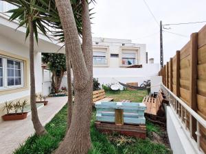 a house with palm trees and a bench in the yard at Cloud to Chill Surfhouse Baleal in Ferrel