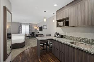 a hotel room with a kitchen and a bed at Home Inn & Suites Saskatoon South in Saskatoon