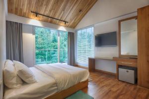 a bedroom with a large bed and a large window at Moksha Riverside Resort in Kasol