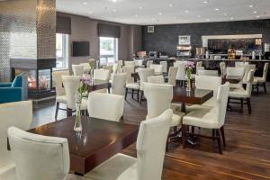 un restaurant avec des chaises et des tables blanches et une cheminée dans l'établissement Home Inn & Suites Regina Airport, à Regina