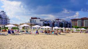 a group of people sitting on a beach with umbrellas at Апартамент Сънрайз Обзор - Apartment Sunrise Obzor in Obzor