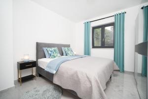 a bedroom with a bed with blue curtains and a window at Villa Apartments Lela in Rabac