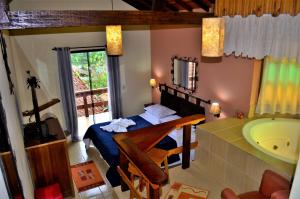 baño con bañera, cama y lavamanos en Pousada Palma Chalés, en Monte Verde