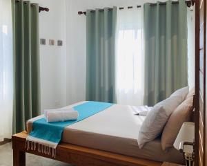 a bed in a bedroom with green curtains at Chez Coco in Pointe Au Sel 