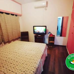 Habitación de hotel con cama y TV en "El Pelícano" Hostal en Maldonado