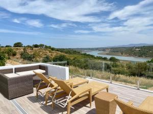 a patio with a table and chairs and a view of a river at Monte Do Zambujeiro in Vila Nova de Milfontes