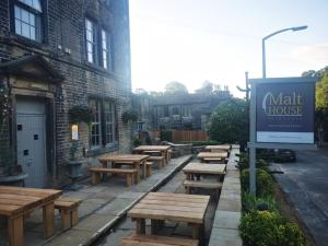 a row of wooden tables and benches outside a building at The Malthouse in Halifax