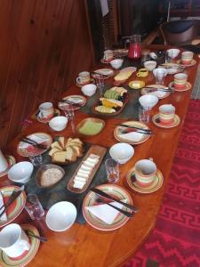uma mesa de madeira coberta com pratos e tigelas de comida em Refugio Las Raices em Malalcahuello
