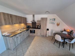 una cocina con armarios de madera y una mesa con sillas. en Oberdeck, en Neuharlingersiel