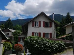 a white house with red shutters and mountains in the background at GÎTE REDROOSTER HOME - 160m2, 4 ch, 2 sdb, fibre, parking, sauna, bain à remous in Theys