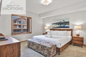 a bedroom with a bed and a desk and a window at White Spruce Lodge by Spring Creek Vacations in Canmore