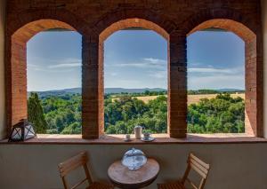 a room with three arched windows with a table and chairs at Palazzo Luci in Colle di Val d'Elsa