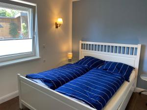 a bed with blue pillows on it with a window at Ferienwohnung Nina Lütjenburg Klamp Ostsee in Lütjenburg