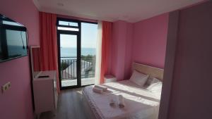 een slaapkamer met een bed met roze muren en een balkon bij Guest House ETM in Makhinjauri