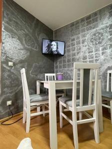 een witte tafel en stoelen met een tv aan de muur bij Prva Apartment in Novi Pazar