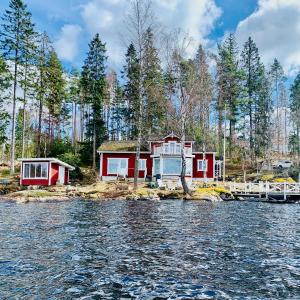 ein Haus am Ufer eines Wasserkörpers in der Unterkunft "Talludden" by the lake Årydssjön, in Furuby