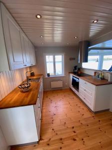 a kitchen with white cabinets and a wooden floor at "Talludden" by the lake Årydssjön, in Furuby