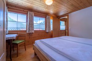 Un dormitorio con cama, escritorio y ventanas en Ferienbauernhof Berlinger, en Au im Bregenzerwald 57 fotos más