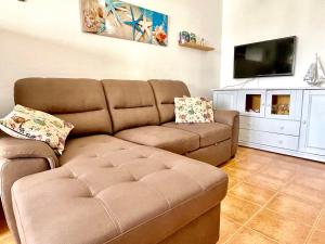 a living room with a couch and a flat screen tv at Eslanzarote Turtle House, Super wifi, Sea views in Caleta de Caballo
