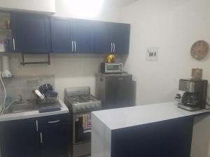 - une cuisine avec des placards bleus, une cuisinière et un évier dans l'établissement El Arrecife: Apartamento con alberca a 10 minutos de la playa, à Acapulco