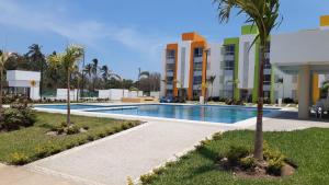 a swimming pool with palm trees in front of a building at El Arrecife: Apartamento con alberca a 10 minutos de la playa in Acapulco