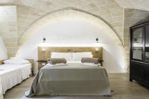 two beds in a room with a stone wall at Dimora Le Site in Torre Suda